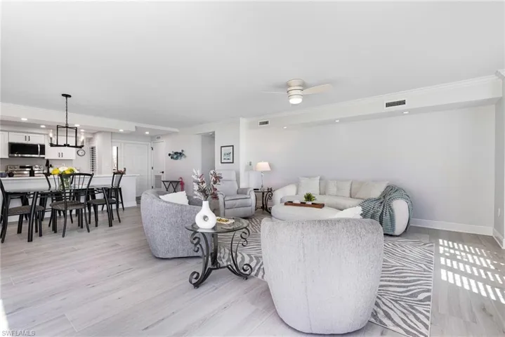 Living room with light hardwood / wood-style floors, crown molding, and ceiling fan with notable chandelier