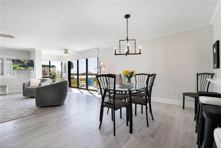 Dining room featuring crown molding, ceiling fan with notable chandelier, and light wood-type flooring
