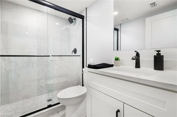 Bathroom with toilet, vanity, and a shower with door