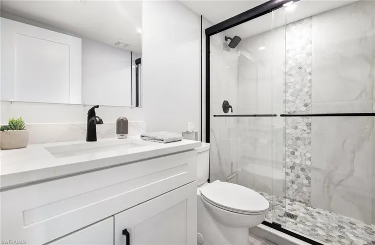 Bathroom featuring vanity, toilet, and an enclosed shower