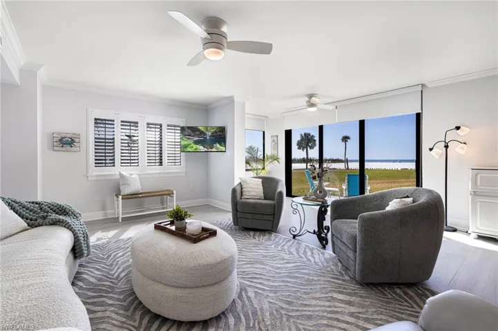 Living room with ornamental molding, hardwood / wood-style flooring, and ceiling fan