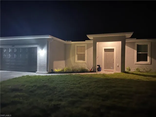 Contemporary stucco exterior with a gray panel garage door, covered entry, and front landscaping