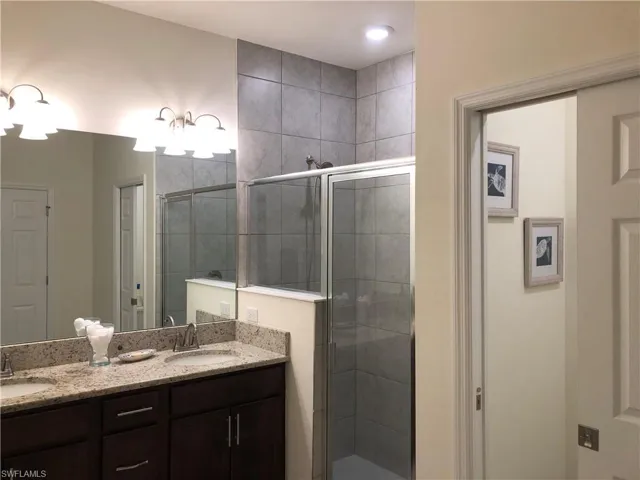 Spacious bathroom featuring a dual vanity with light-toned countertops, dark wood cabinetry, and chrome fixtures
