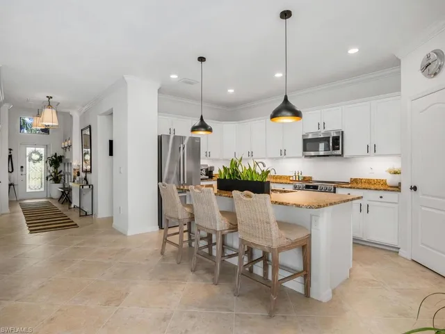 Kitchen featuring a kitchen island with sink, appliances with stainless steel finishes, a breakfast bar area, and white cabinets
