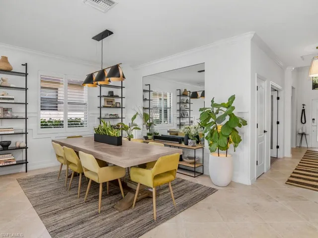 Dining space with crown molding and light tile patterned floors