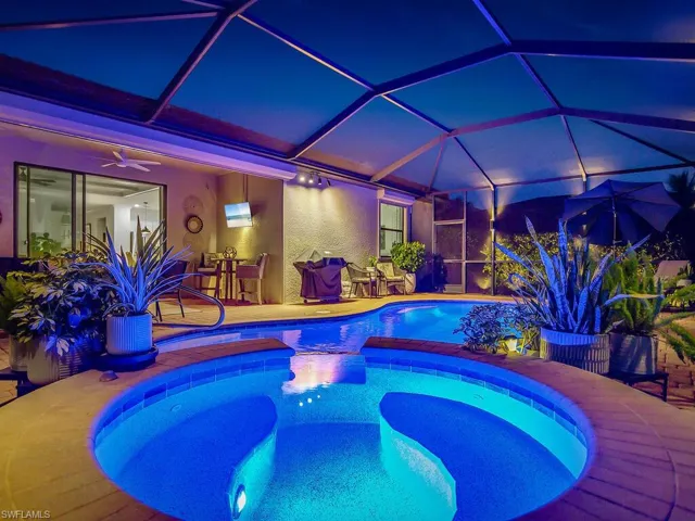 Pool at twilight featuring ceiling fan, a patio area, and glass enclosure