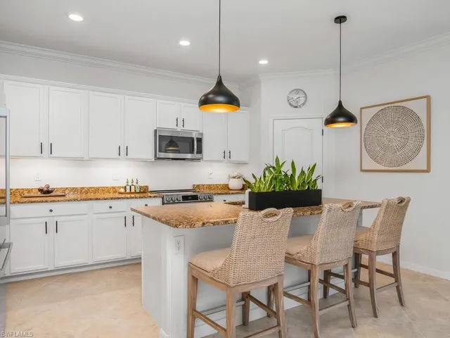 Kitchen featuring a center island, white cabinetry, decorative light fixtures, and stainless steel appliances