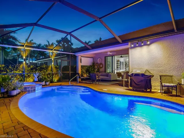 Pool at night with a patio area, outdoor lounge area, ceiling fan, and a lanai