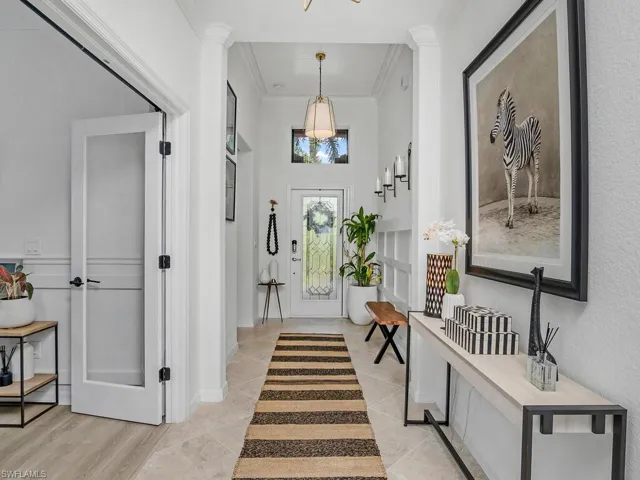 Entrance foyer featuring crown molding, light hardwood / wood-style floors, and ornate columns