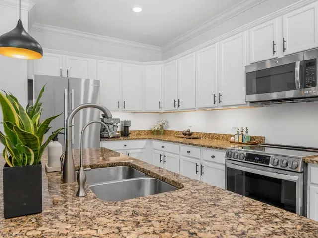 Kitchen featuring white cabinets, appliances with stainless steel finishes, stone countertops, and sink