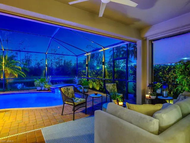 View of patio with an outdoor living space, ceiling fan, and glass enclosure