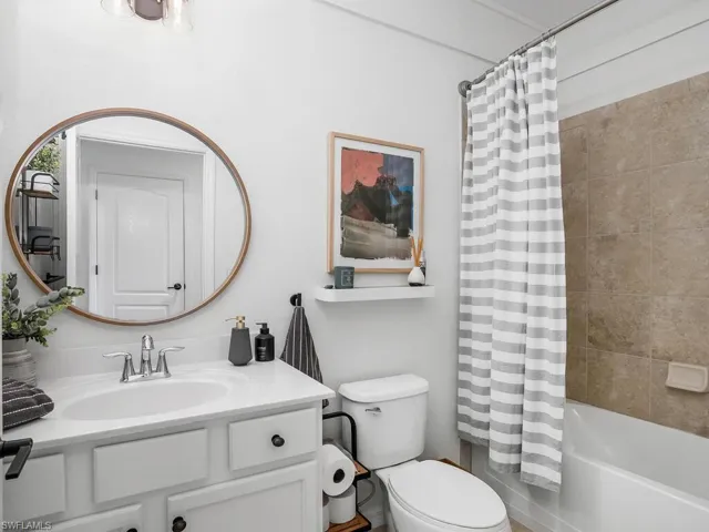 Full bathroom with shower / bathtub combination with curtain, toilet, and vanity