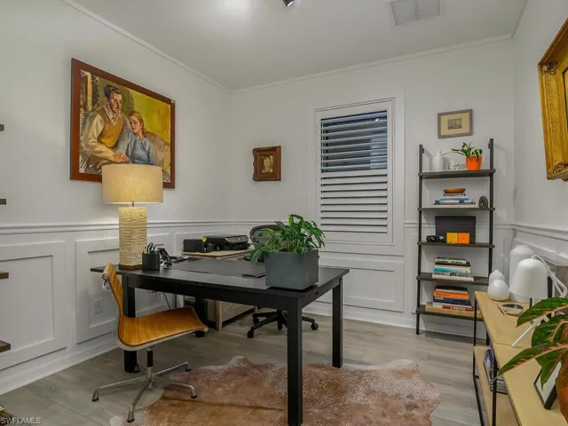 Office space with ornamental molding and light hardwood / wood-style flooring