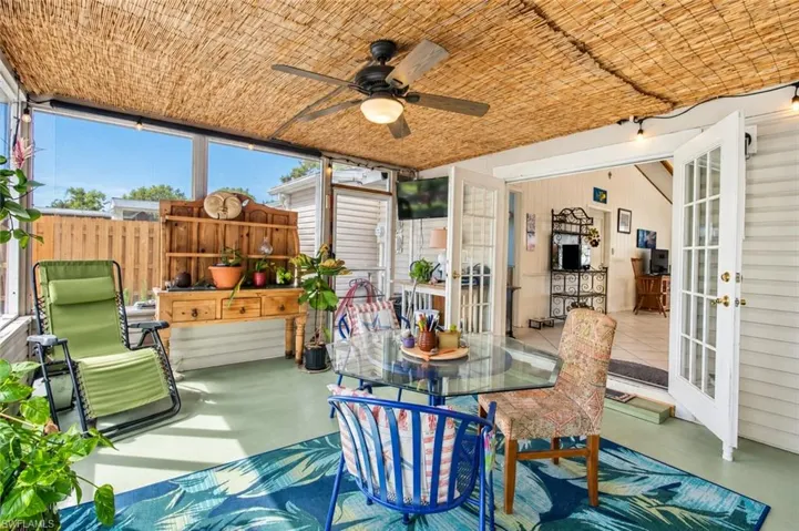 Enclosed sunroom featuring a natural woven ceiling, ceiling fan, expansive window walls, and double glass-pane doors