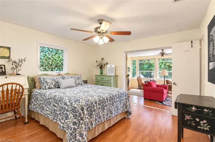 Bedroom featuring wood-finish flooring, a multi-blade ceiling fan with integrated lighting, and multiple windows
