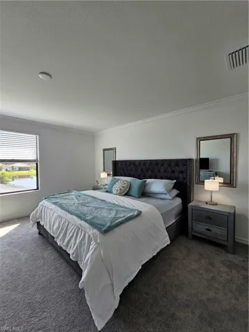 Carpeted bedroom featuring a textured ceiling and crown molding