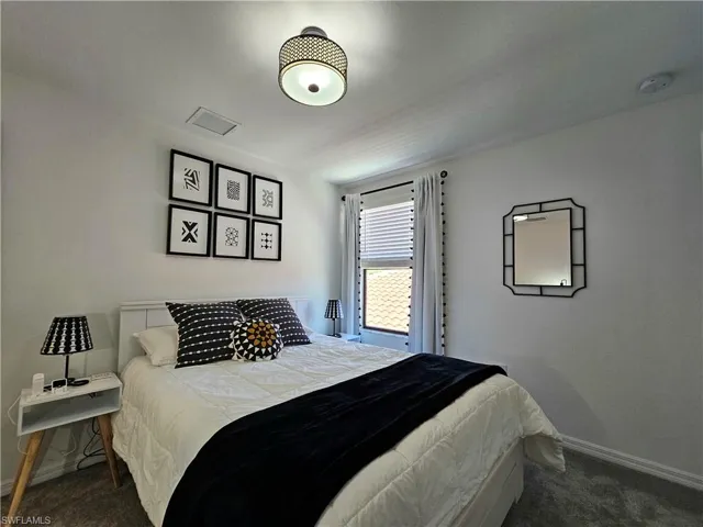 Bedroom featuring dark colored carpet and baseboards