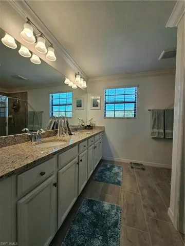 Bathroom with ornamental molding, a stall shower, and double vanity