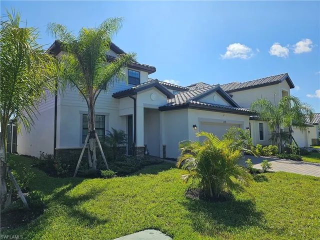 Mediterranean / spanish house featuring a tile roof, an attached garage, a front lawn, and stucco siding
