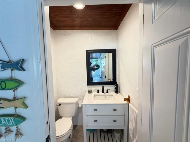 Half bath with a textured wall, wooden ceiling, and vanity