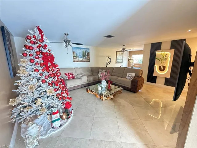 Living room with light tile patterned floors and a ceiling fan