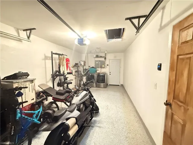 Garage featuring washer and dryer, electric panel, and a garage door opener