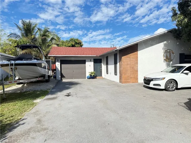 View of side of property with an attached garage, stucco siding, and driveway