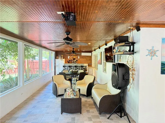 Sunroom with wood ceiling, wooden walls, and an AC wall unit