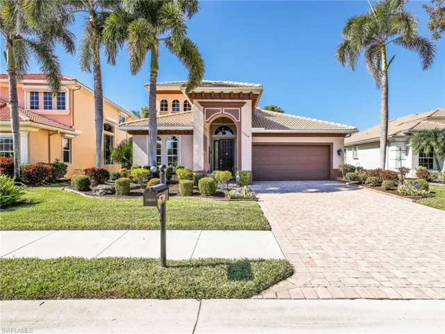 Mediterranean / spanish-style home featuring stucco siding, decorative driveway, a front yard, an attached garage, and a tiled roof