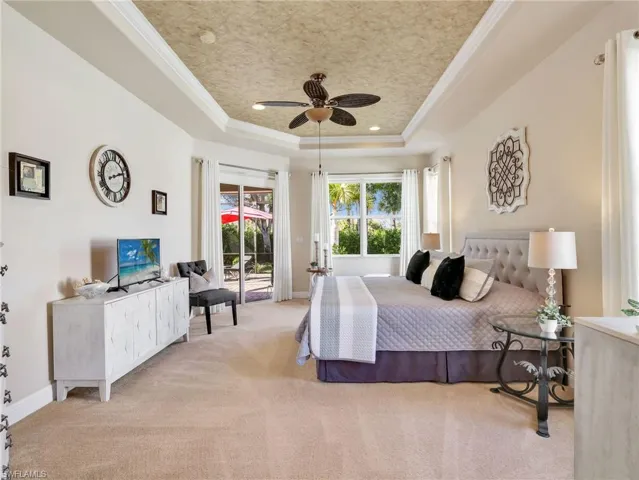 Bedroom with ornamental molding, access to exterior, carpet flooring, ceiling fan, and a raised ceiling
