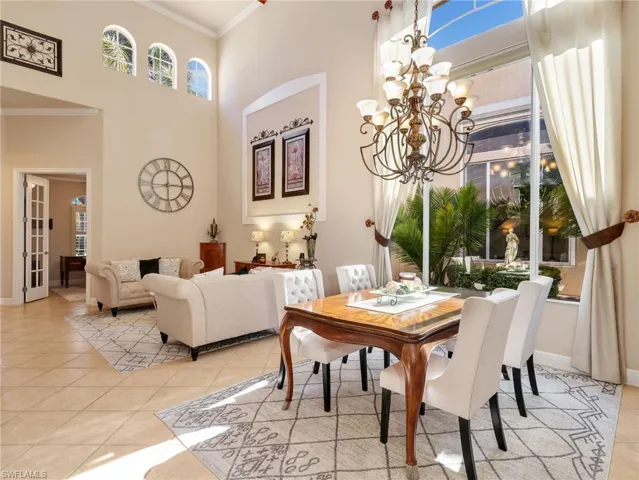 Dining room featuring a high ceiling, crown molding, suspended lighting, and light tile patterned floors