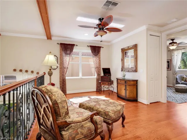 Sitting room with a ceiling fan, wood finished floors, crown molding, plenty of natural light, and beam ceiling