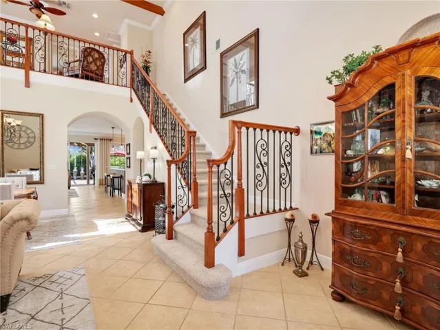 Staircase featuring arched walkways, ornamental molding, a high ceiling, tile patterned flooring, and hanging lights