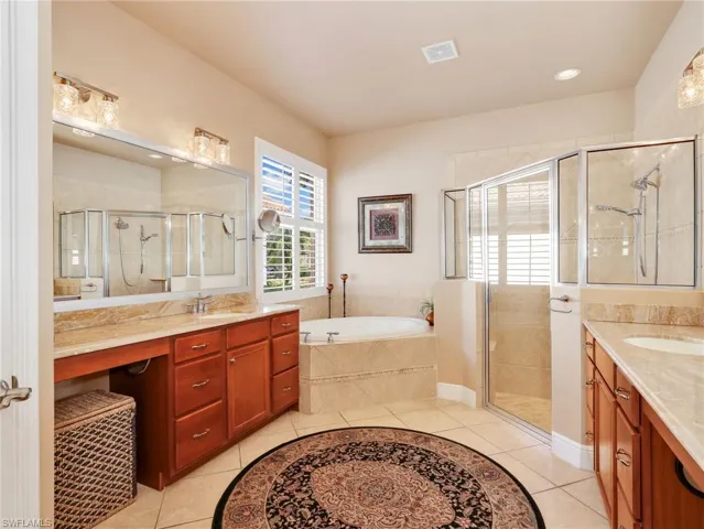 Full bathroom with two vanities, a garden tub, a shower stall, light tile patterned flooring, and recessed lighting
