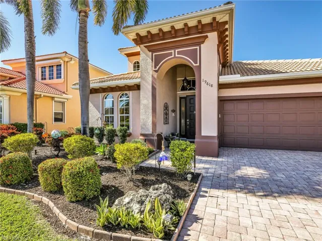 View of exterior entry with stucco siding, a tiled roof, driveway, and an attached garage