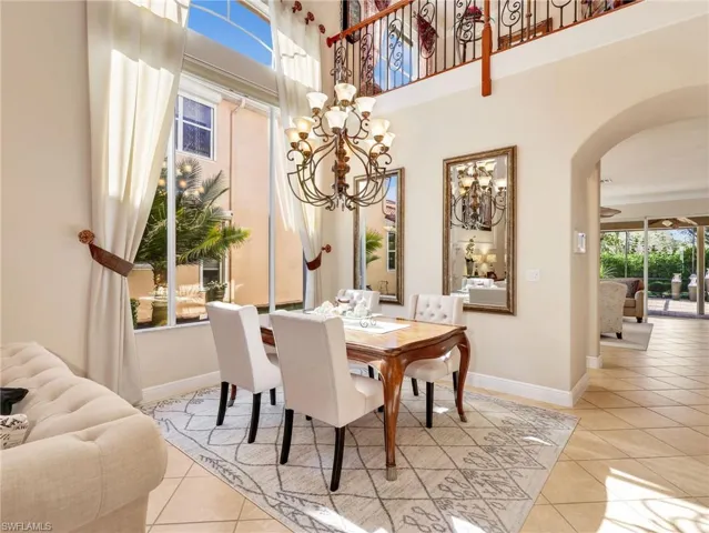Dining space featuring arched walkways, hanging lights, light tile patterned floors, and a high ceiling