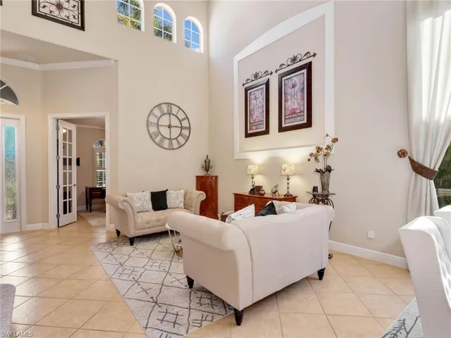 Living area with a high ceiling, light tile patterned floors, and crown molding