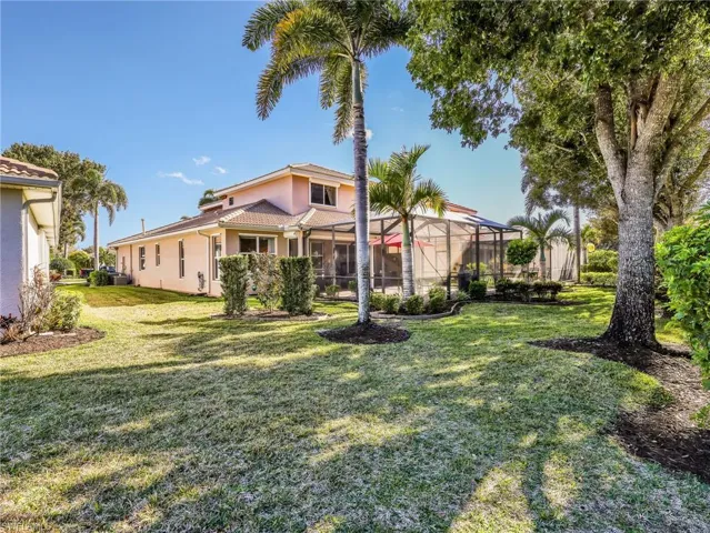 Back of house with a sunroom, a yard, stucco siding, and a lanai