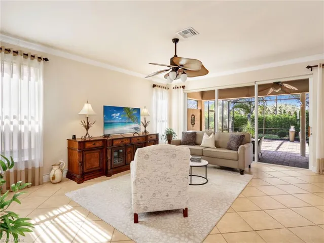 Living room with light tile patterned flooring, a ceiling fan, and ornamental molding