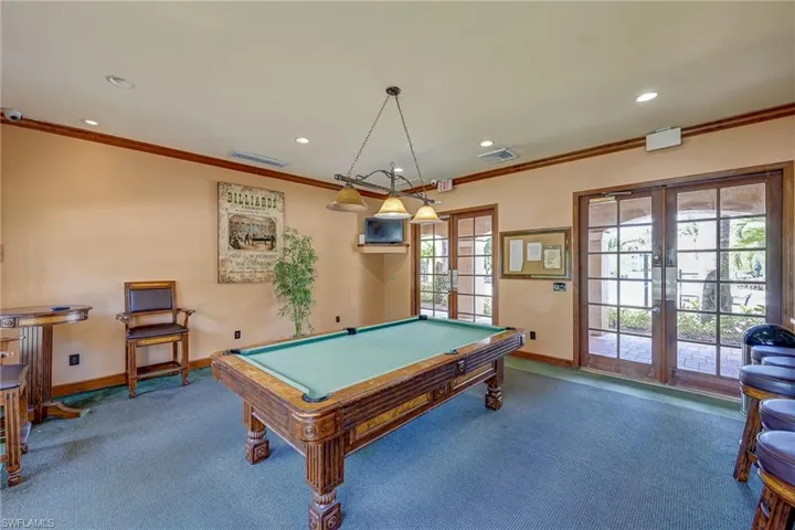 Recessed lighting, triple-pendant fixture, crown molding, and dual glass-panel exterior doors with wood trim