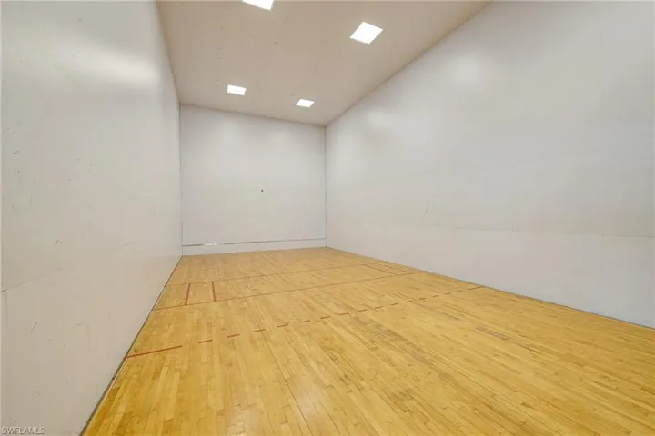 Recreational court featuring wood-finish flooring, high-impact wall panels, and recessed ceiling lighting