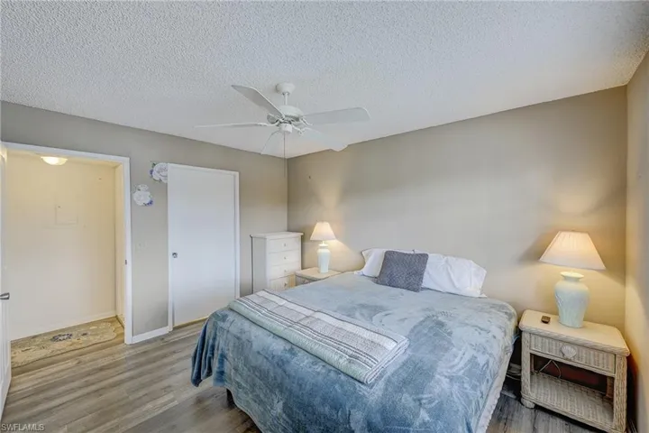 Wood-finish flooring, white ceiling fan, and solid-core interior door