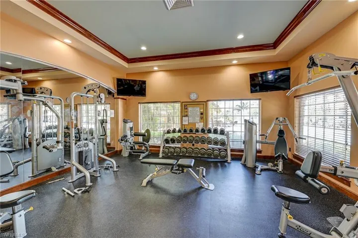 Fitness facility featuring rubberized flooring, expansive wall-to-wall mirrors, recessed lighting, and crown molding