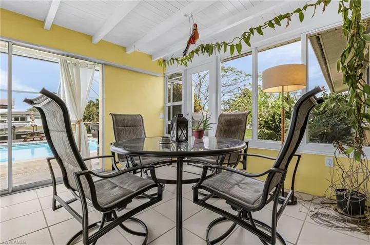 Sunroom featuring beamed ceiling, healthy amount of natural light, and french doors