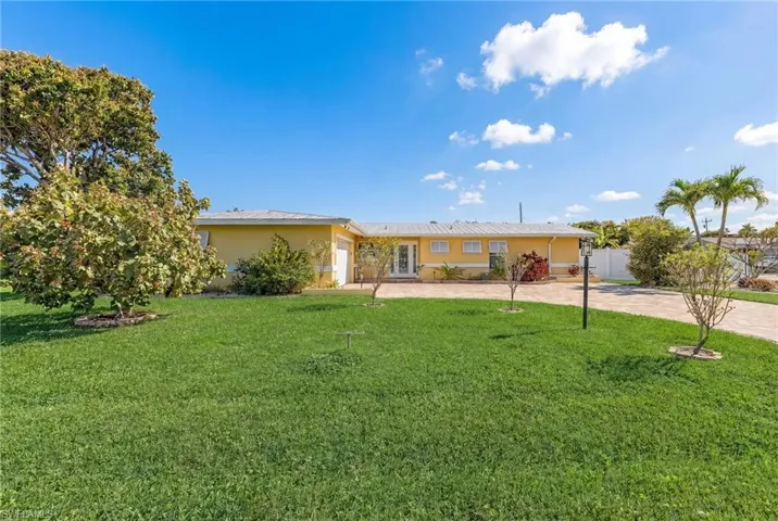 Single story home with stucco siding, a front lawn, a garage, and driveway