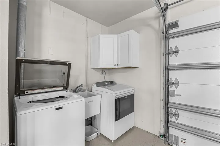 Laundry area with washer / dryer, cabinet space, and concrete flooring