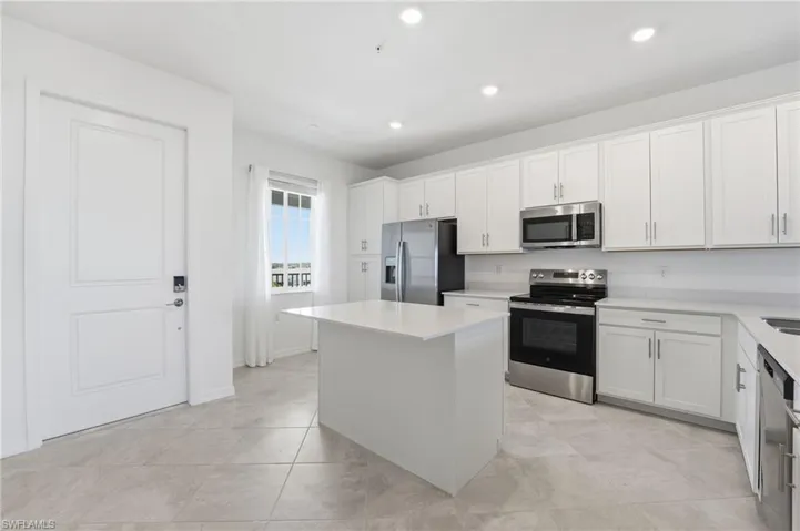 Kitchen with appliances with stainless steel finishes, white cabinetry, a center island, recessed lighting, and light tile patterned floors