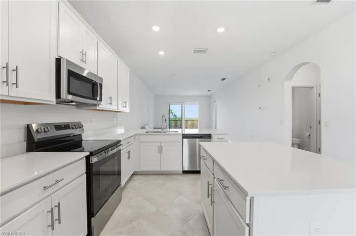 Kitchen featuring stainless steel appliances, white cabinetry, a center island, recessed lighting, and a peninsula