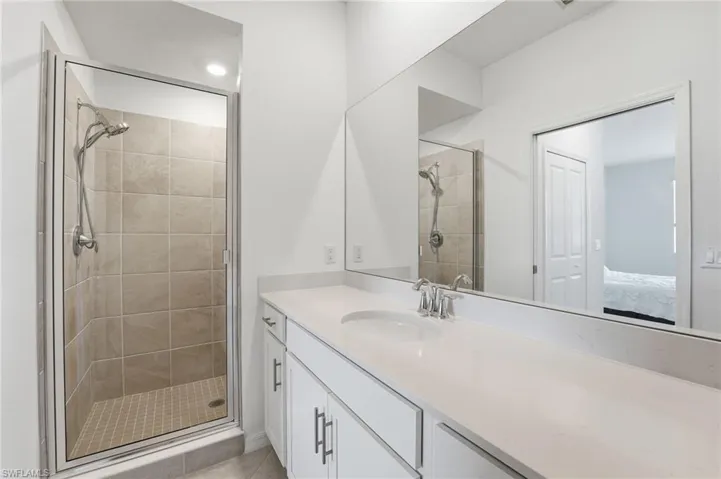 Full bath with a shower stall, vanity, ensuite bathroom, and light tile patterned floors