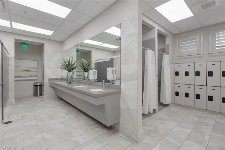 Full bathroom with double vanity, a stall shower, tile walls, and a drop ceiling